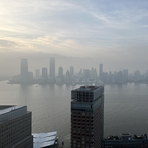 Hazy view of Jersey City skyscrapers. Battery Park City, Manhattan.