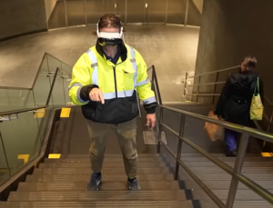Man wearing Apple Vision Pro goggles stops to respond to text messages on the stairs at Times Square station.